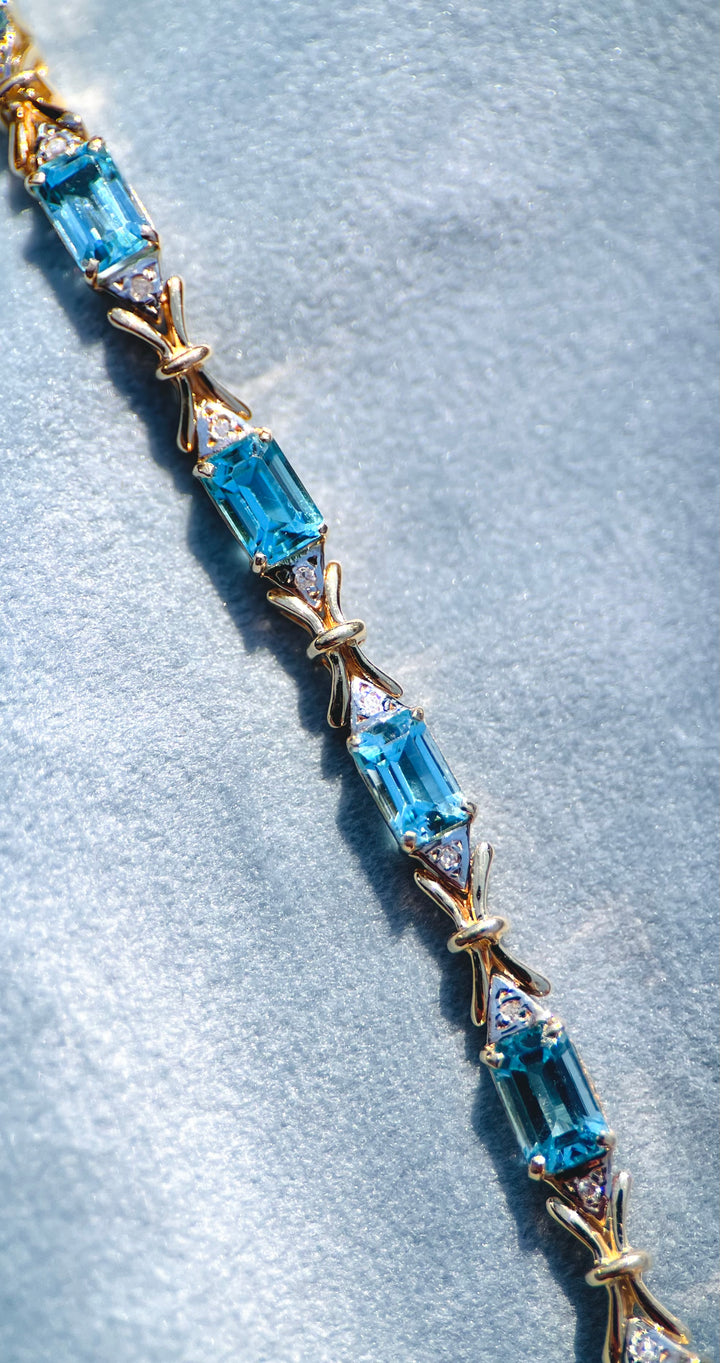 “Frost and Bows” Emerald Cut Blue Topaz with Diamond Accents in 14k Yellow Gold